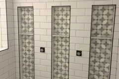 4′′ × 8′′ Ceramic tile, subway pattern. Niches: Marble mosaic tile with white Carrara shelves and oil-bronze Schluter edges, in Centennial, Colorado