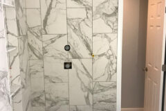 Shower Wall: 12′′ × 24′′ Porcelain tile, vertical subway pattern. Shower Niche: 2′′ × 2′′ Hexagon marble with three quartz shelves, in Thornton, Colorado