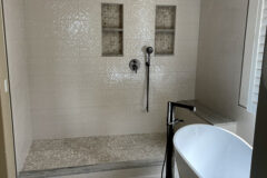 Shower Walls: 10′′ × 30′′ Decorative ceramic tile. Niche: Travertine mosaic with quartzite shelves and Schluter edge. Bench & Curb: Quartzite. Bathroom Floor: 12′′ × 24′′ Porcelain tile, subway pattern, in Broomfield, Colorado