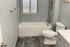 Top Surround: 3′′ × 12′′ Ceramic tile, subway pattern, round pencil edge. Window Sill: Quartz. Bathroom Floor: 12′′ × 24′′ Porcelain tile. Baseboard: Porcelain tile with Schluter edge, in Morrison, Colorado